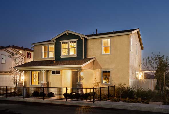 Evening view of front of model home with lights on.